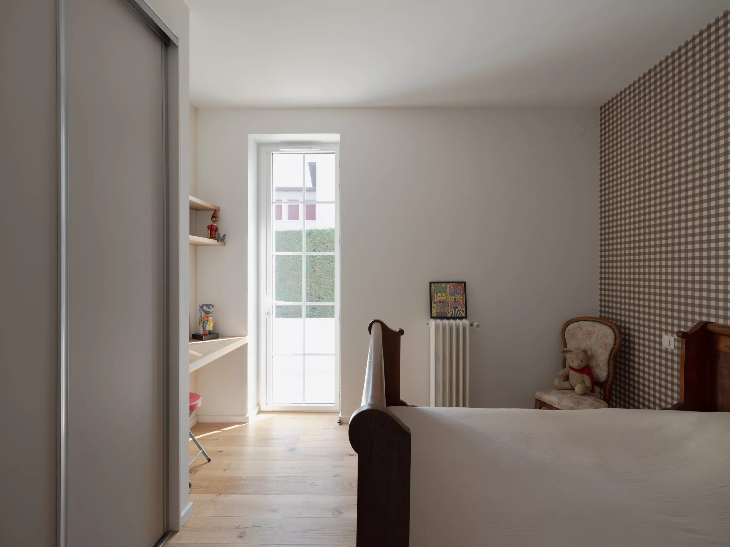 Chambre rénovée avec parquet chêne clair, lit ancien et papier peint à carreaux